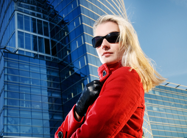 Beautiful young blond woman outdoors. Modern building behind her - Foto, immagini