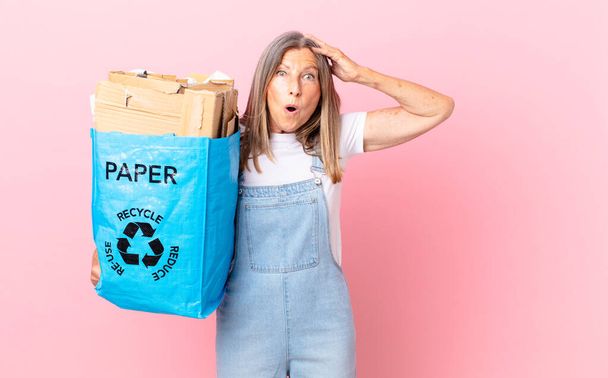pretty middle age woman feeling stressed, anxious or scared, with hands on head recycling cardboard concept - 写真・画像