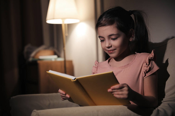 Little girl reading fairy tale at home in evening - Φωτογραφία, εικόνα