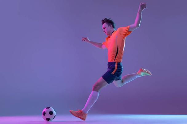 One male soccer football player in action and motion isolated on gradient lilac pink background in neon light - Foto, imagen