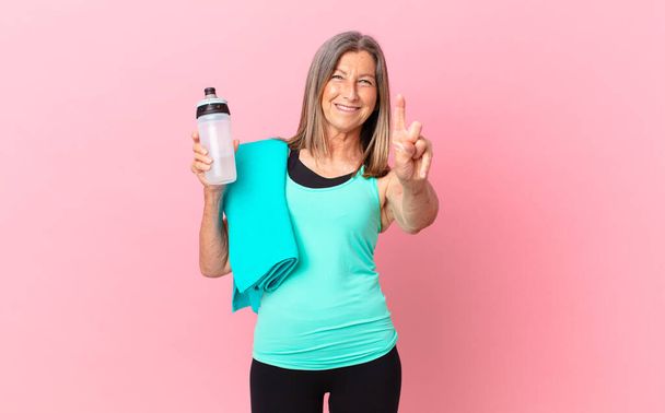 pretty middle age woman smiling and looking friendly, showing number one. fitness concept - Foto, imagen