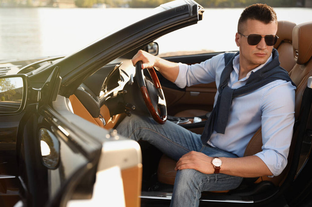 Handsome young man in luxury convertible car outdoors - Photo, image