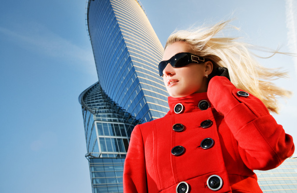 Beautiful young blond woman outdoors. Modern building behind her - Photo, Image