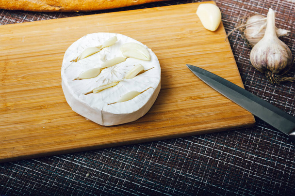 DIY paistettua juustoa camembert opetusta askel askeleelta. vaihe 2 tehdä leikkauksia camembert ja aseta valkosipuli osaksi cuts.cheese valkoinen hometta. - Valokuva, kuva