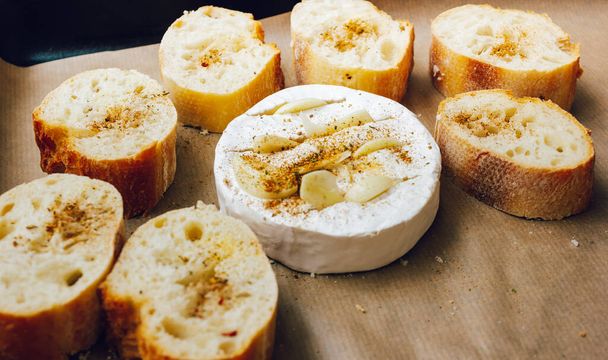 DIY gebackenen Käse Camembert Anleitung Schritt für Schritt. Schritt 3 Brot und Camembert auf ein Backblech mit Backpapier legen und die Gewürze hinzufügen. Käse mit weißem Schimmelpilz - Foto, Bild