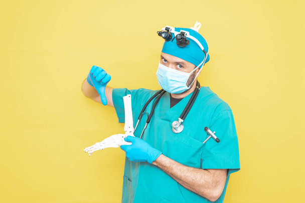 jovem médico-cirurgião vestido de verde sobre fundo amarelo. - Foto, Imagem