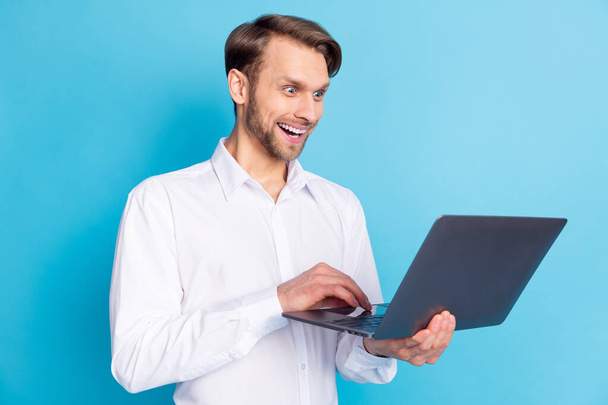 Photo of amazed happy cheerful young businessman look laptop news isolated on pastel blue color background - Foto, Imagem