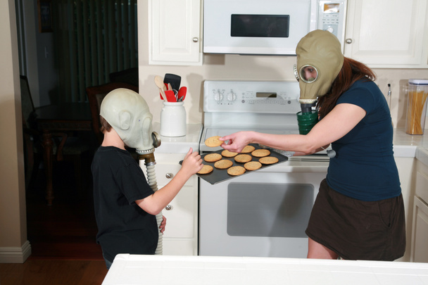 мати й син люблять арахісове масло на кухні, а після ядерної зими носили газові маски. Глобальний день печива. Молода сім'я любить печиво під час носіння протигазів через глобальне потепління. після уроків. печиво - Фото, зображення