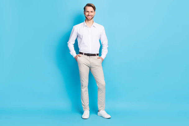 Full length photo of attractive young man smile hold hands pockets smile good mood worker isolated on blue color background - Фото, изображение