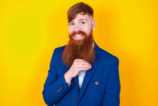 Улыбающийся молодой красивый бородатый мужчина с длинной бородой смотрит в камеру. счастливчик - Фото, изображение