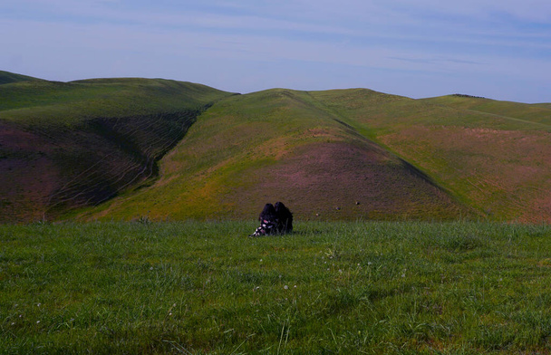                The girls are sitting in the middle of a wide hill                 - Fotó, kép
