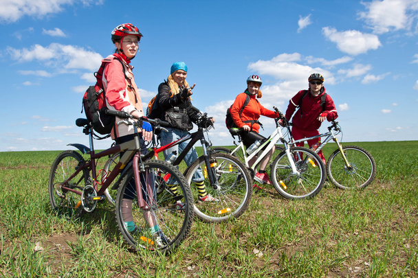 Ryhmä neljää aikuista polkupyörillä maaseudulla
. - Valokuva, kuva
