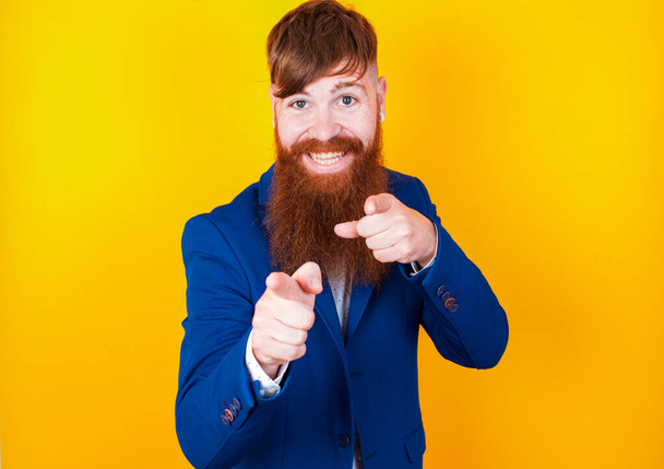 бородатый белый мужчина в синей куртке позирует на желтом фоне - Фото, изображение