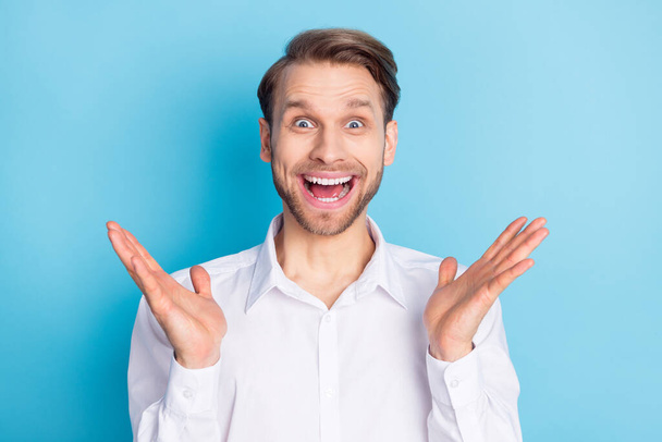 Photo of amazed happy excited young blonde man raise hands shock present isolated on blue color background - Photo, Image