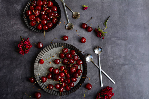 Sweet cherries on plates on a gray background, top view. Horizontal image. - Фото, изображение