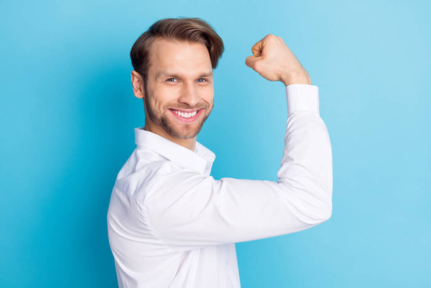 Profile side photo of happy positive young man show biceps winner smile isolated on pastel blue color background - Foto, imagen