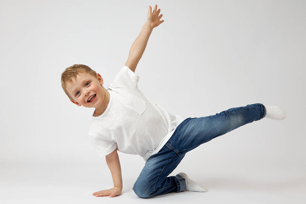 Happy child with blue eyes and a toothy smile is engaged in fitness. - Фото, зображення
