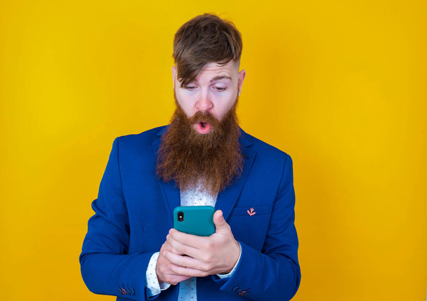 homem barbudo com telefone celular em um fundo amarelo - Foto, Imagem