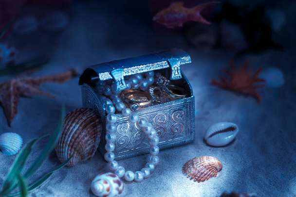 Fantasía sobre el tema de los tesoros que yacen en el fondo del mar o el océano. Joyería en un cofre bajo el agua. - Foto, Imagen