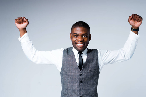 Happy african american businessman in a suit rejoices clenching his hands into fists and raising them - Photo, Image