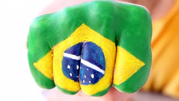brazilský fotbalový fotbalový fanoušek dělá Vítězné gesto, brazilská vlajka na pěst - Záběry, video