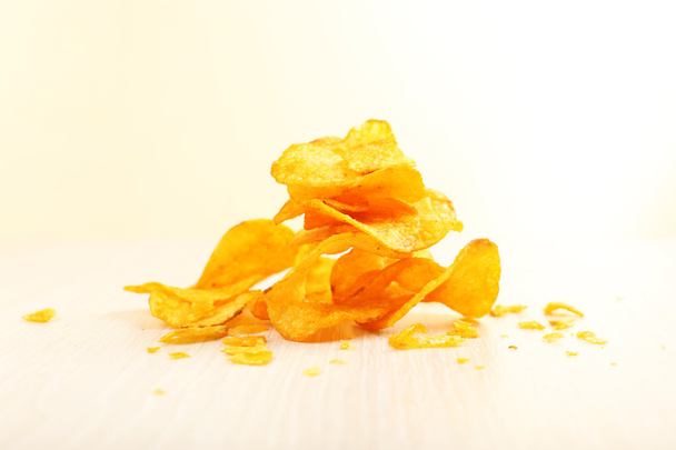 Heap of homemade potato chips on light background - Foto, afbeelding