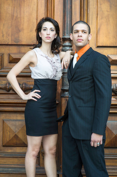 A young couple of businessman and businesswoman are standing together in the front of the office door and confidently looking forward - Foto, Imagem