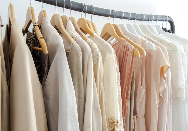 Stylowe damskie ubrania wiszące na stojaku naturalne kolory, koncepcja trending, pastelowe kolory w białym pokoju nowoczesny design zbliżenie przechowywania - Zdjęcie, obraz
