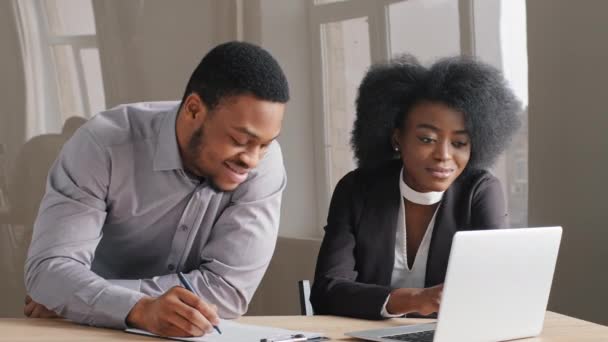 Lächelnde junge afrikanische Büroangestellte diskutiert neue Ideen, plant Projekte mit männlichen Kollegen im Büro. Millennial-Frau kooperiert bei Treffen mit Finanzberaterin - Filmmaterial, Video