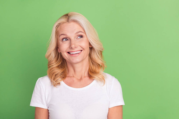 Photo portrait elder woman looking copyspace in white t-shirt smiling isolated pastel green color background - Fotó, kép