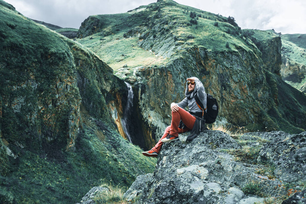 Traveler man sits on a stone in the mountains - 写真・画像