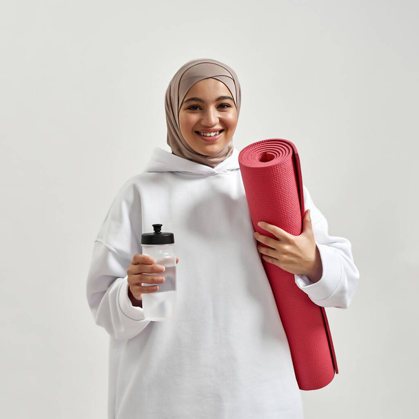 Portrait of arabian girl holding mat and water bottle - Photo, Image
