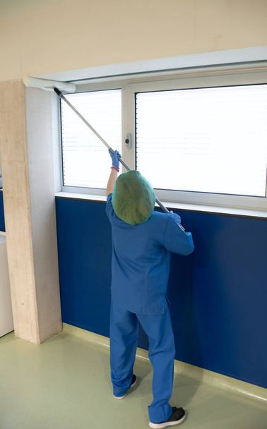 専用ブラシで事前手術室の窓を掃除する病院の清掃サービスの女。衛生概念 - 写真・画像