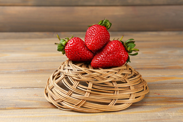 Red ripe strawberries in wicker basket on wooden background - Photo, image