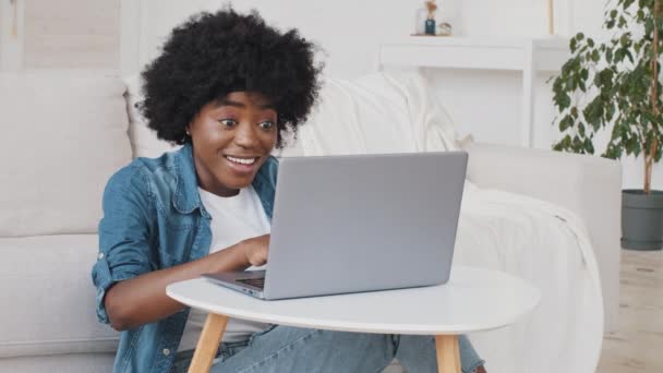 Szczęśliwa Afrykanka czytająca wspaniałe wieści czuje się dobrze zaskoczona możliwością pracy. Student dziewczyna dostać online test wynik stypendium na komputer czuć zwycięzca za pomocą spojrzeć na laptopa świętować sukces - Materiał filmowy, wideo
