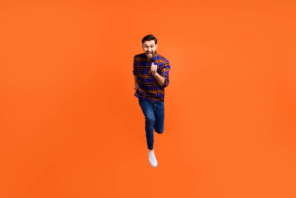 Full size photo of crazy cheerful man jumping running toothy smile isolated on orange color background - Valokuva, kuva