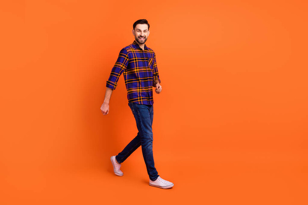 Full size profile photo of satisfied young person walking look camera toothy smile isolated on orange color background - Φωτογραφία, εικόνα