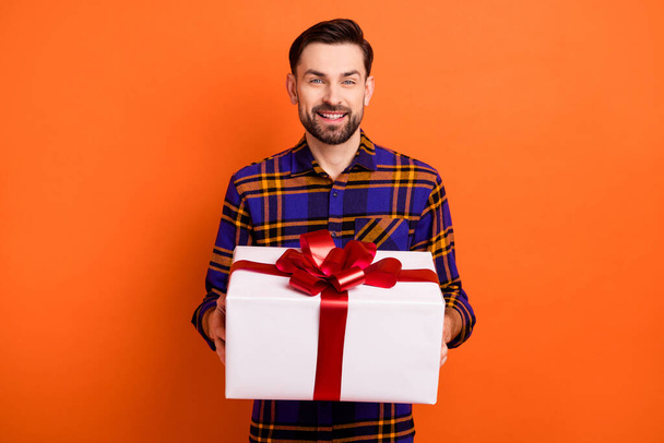 Photo of satisfied young man hands hold giftbox beaming smile look camera isolated on orange color background - Foto, imagen
