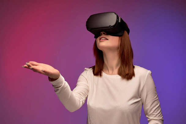 excited young woman in virtual reality helmet, looking into VR glasses screen - Foto, imagen