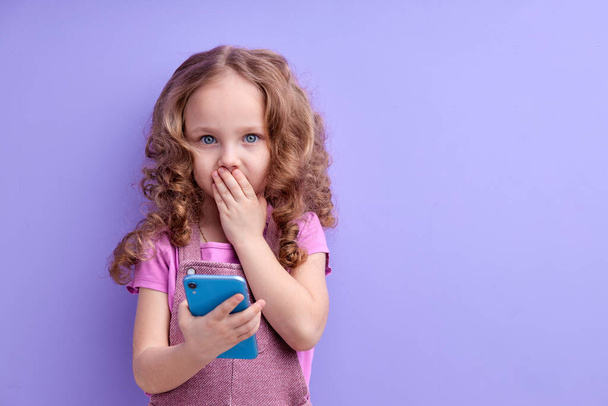 Páni, úžasná aplikace pro děti. překvapená holčička pomocí smartphonu s šokovaným výrazem - Fotografie, Obrázek