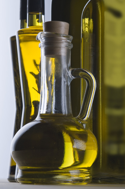 Olive oil bottle still-life over light background, focus on foreground - Фото, изображение