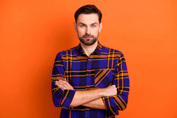 Photo of young handsome brown hair man confident crossed hands serious isolated over orange color background - Foto, Imagem