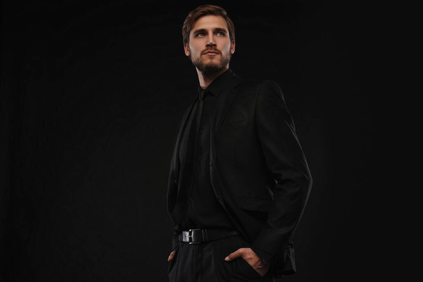 Elegant young handsome man in black suit. Studio fashion portrait - Fotó, kép