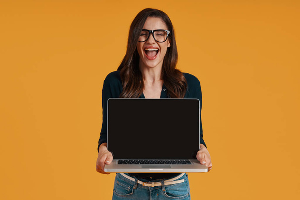 Happy young woman in smart casual clothing pointing copy space at laptop - Φωτογραφία, εικόνα