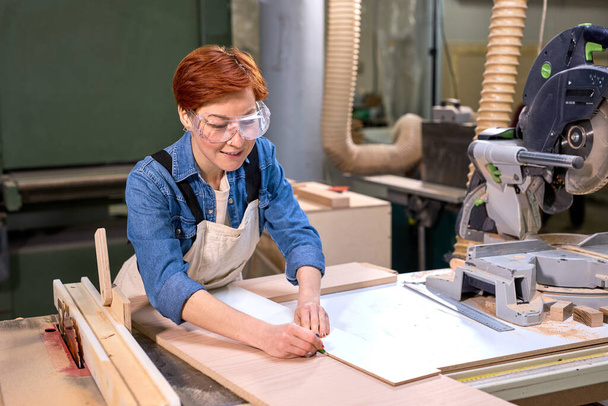 Hardworking female carpenter working as wood designer in small carpentry workshop - Foto, immagini