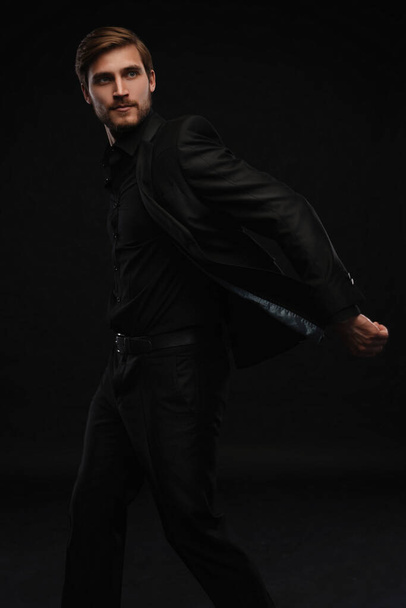 Young man in black suit full body portrait against black background. - Foto, Imagem