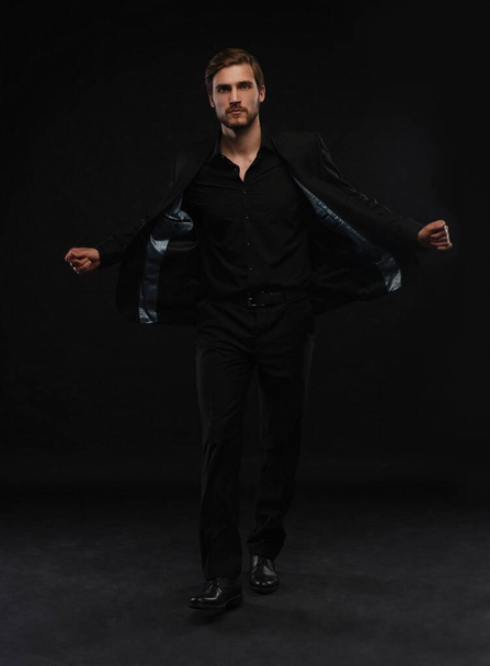 Young man in black suit full body portrait against black background. - Valokuva, kuva