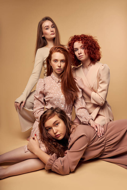 Gorgeous young female models in fashionable dress isolated on beige background - Valokuva, kuva