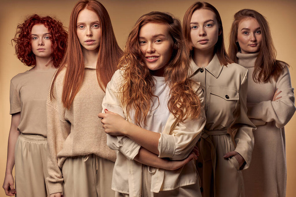 Five red-haired models in beige casual outfit stand isolated on beige background - Fotó, kép