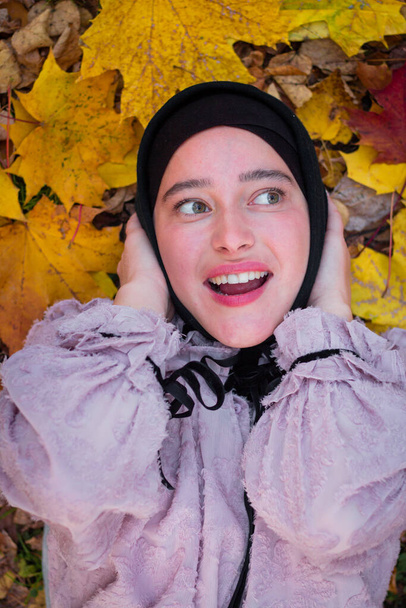 Muslim woman in a hijab on a background of colorful autumn leaves. Beauty photography. Pink blouse. smiles. Autumn leaves. Face close-up. - Photo, Image